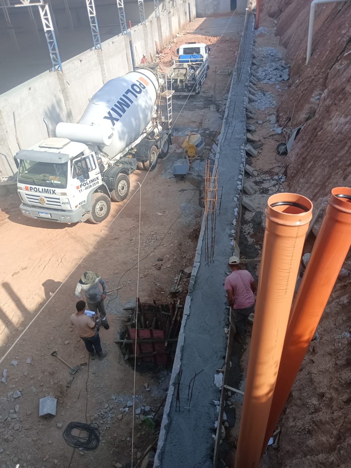 Obra em andamento com caminhão betoneira e tubulação