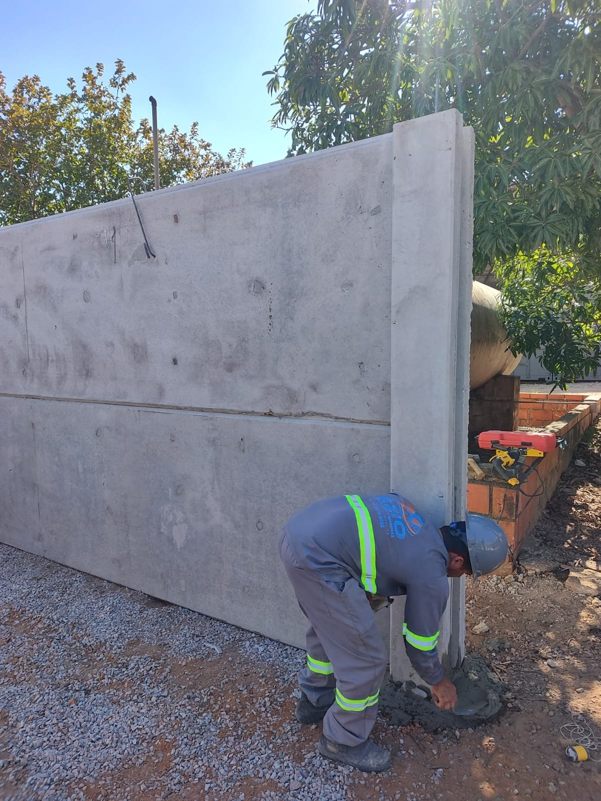 Profissional com uniforme da Ézio assentando placa de concreto